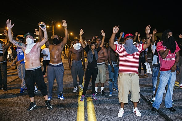 Demonstrators gesture with their hands up after protests in reaction to the shooting of Michael Brown turned violent near Ferguson, Missouri